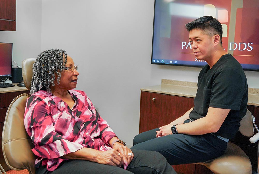 Dr. Paul Lee sits with a female dental patient